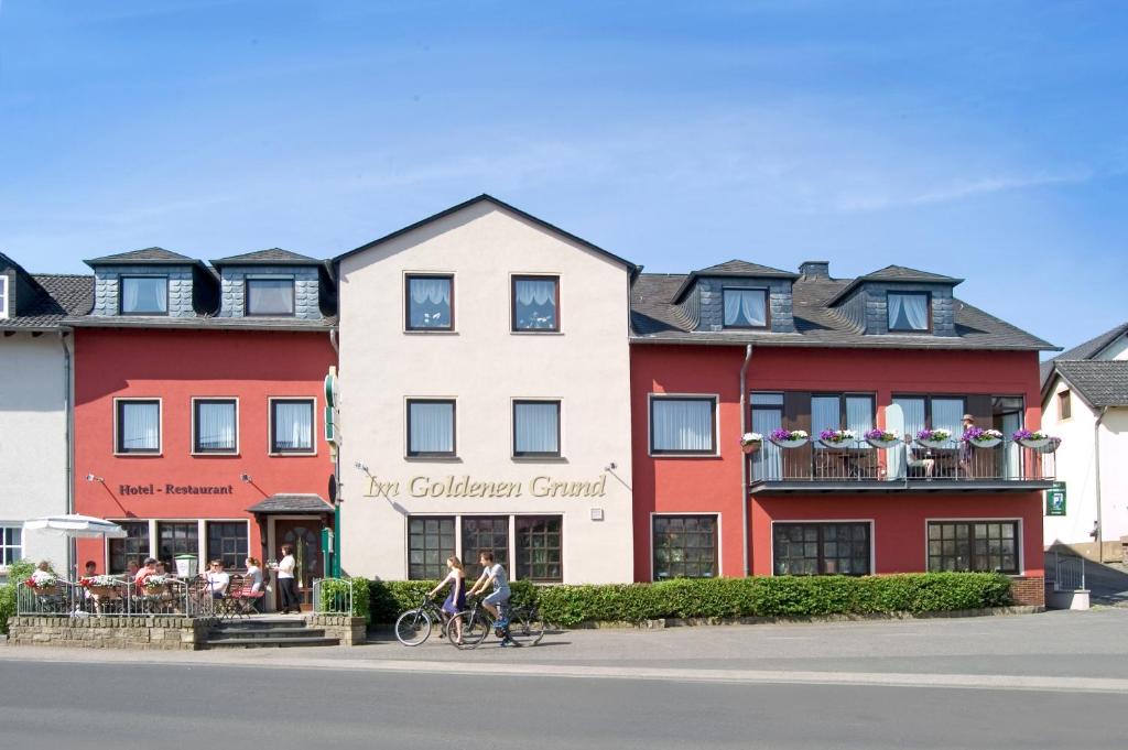 twee mensen op een fiets voor een gebouw bij Hotel-Restaurant Im Goldenen Grund in Körperich