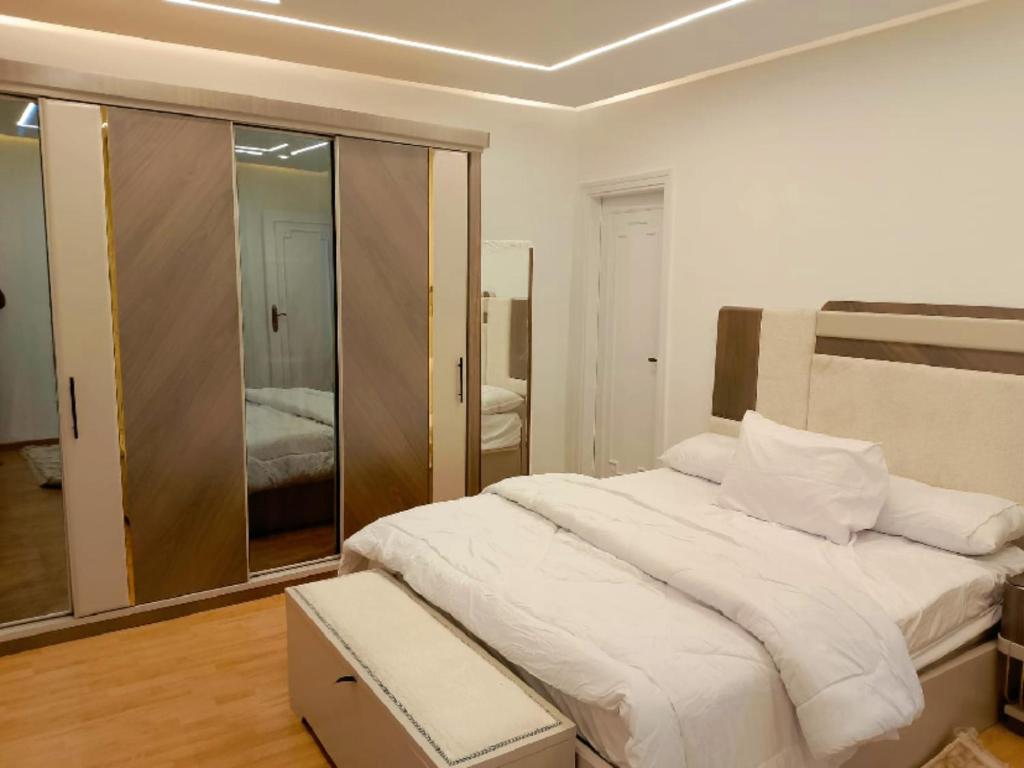 a white bedroom with a large bed and a mirror at النور للاستثمار العقاري بالمنيل in Cairo