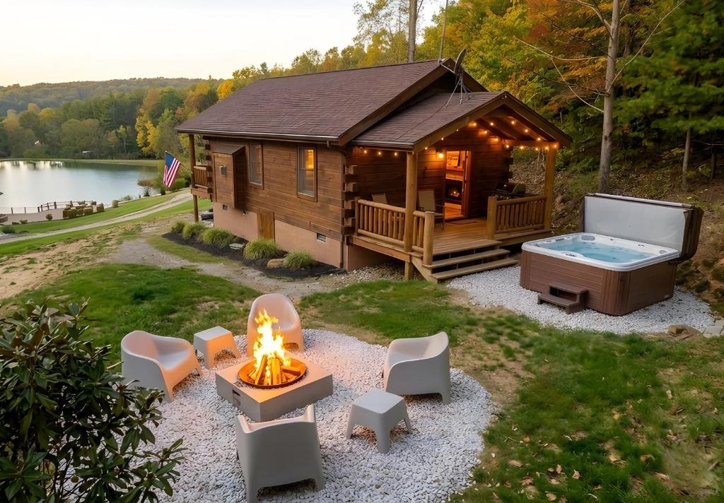 a log cabin with a hot tub and a fire pit at Lake View Cozy Cabin Hocking Hills with Pond and Hot Tub in Rockbridge
