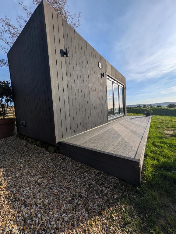 a small house with a wooden deck on a field at The Lookout in Fenny Compton