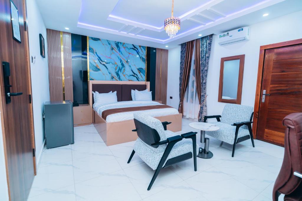 a hotel room with a bed and two chairs at VHS Vinchee Suites II in Lagos