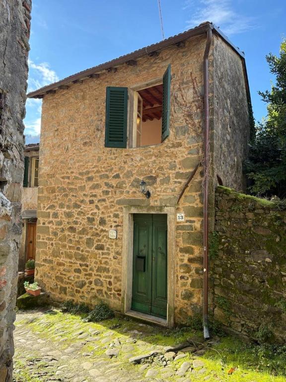 an old brick building with a green door and a window at La Benabbiana in Bagni di Lucca