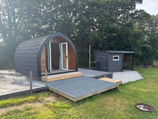 a small cabin with a deck in a field at Trevessa camping pod in Saint Erth