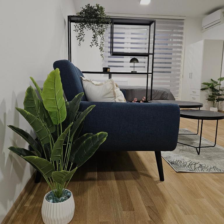 a blue couch in a living room with a plant at Sarajevo s Secret -Airport Apartment East Sarajevo in Donje Mladice