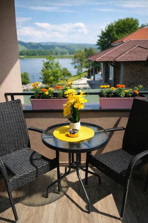 a patio table with two chairs and a vase of flowers on it at Gagin San -apartman na plaži in Veliko Gradište