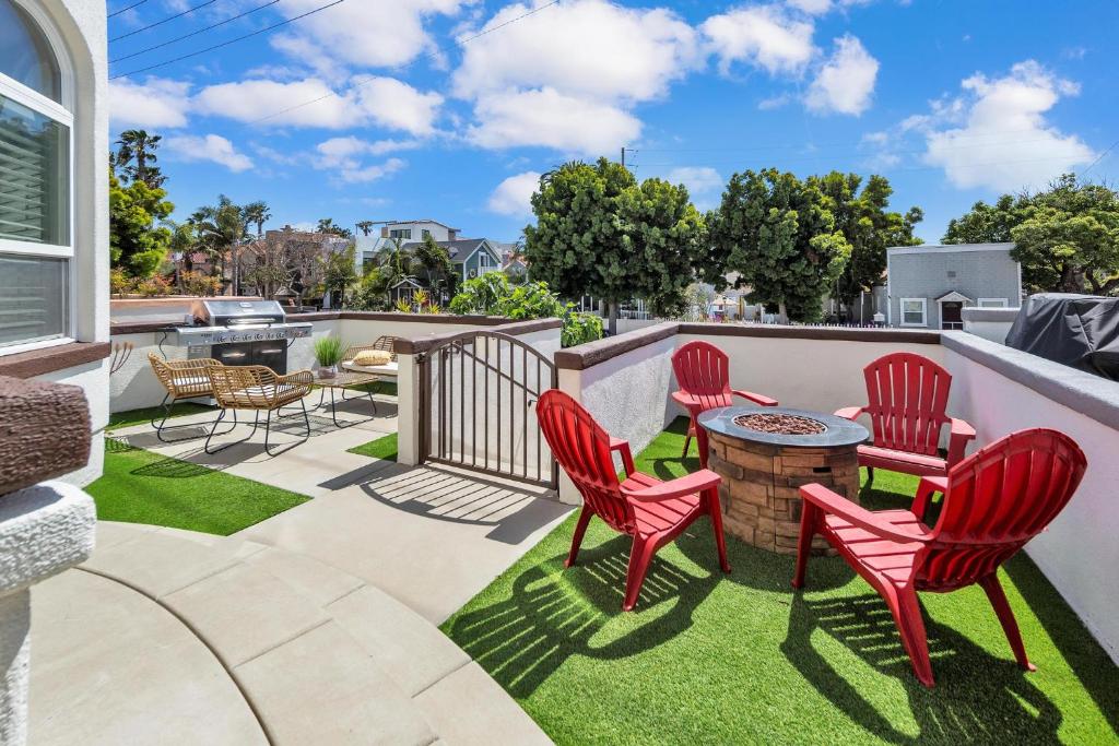 a patio with red chairs and a table on the grass at Near Oceanside Pier! Pirate in Oceanside