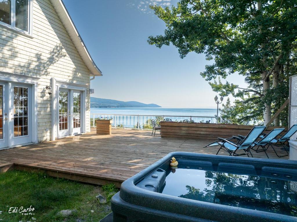 a backyard with a hot tub next to a house at La Maison Jaune in La Malbaie