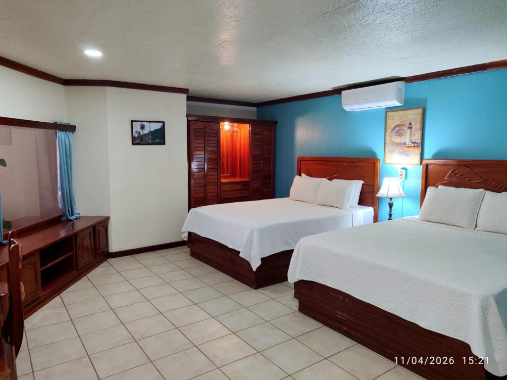 a hotel room with two beds and a television at Fish Hook Marina Hotel in Golfito