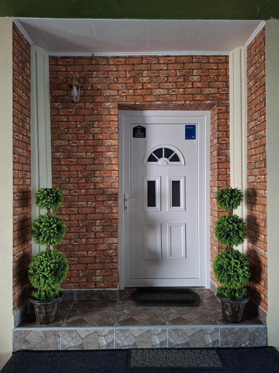 a brick house with a white door and two potted plants at Apartman Duga in Kula