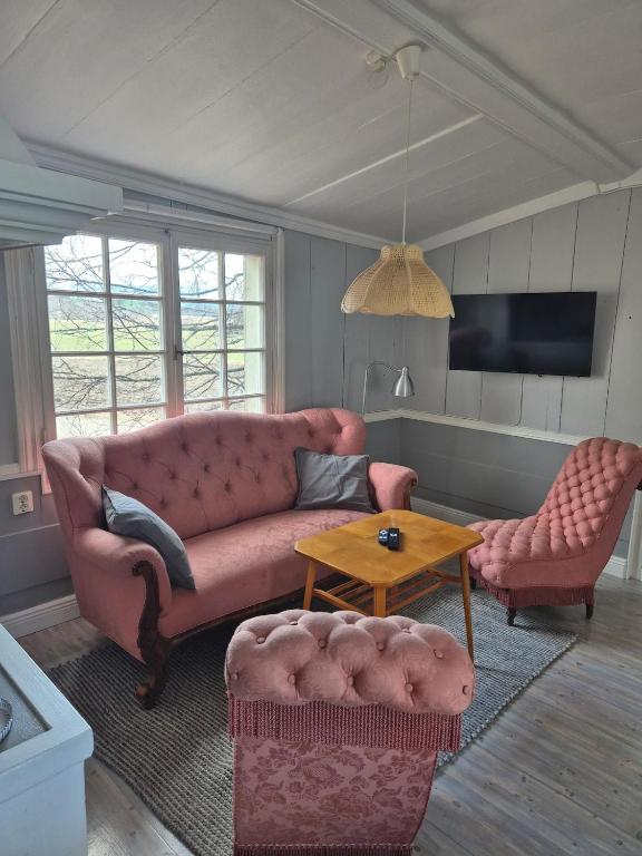 a living room with a pink couch and a table at Vedmyrastugan in Delsbo