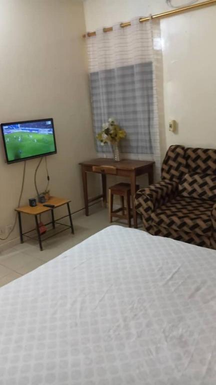 a room with a bed and a couch and a television at Résidence Fatima in Tambacounda