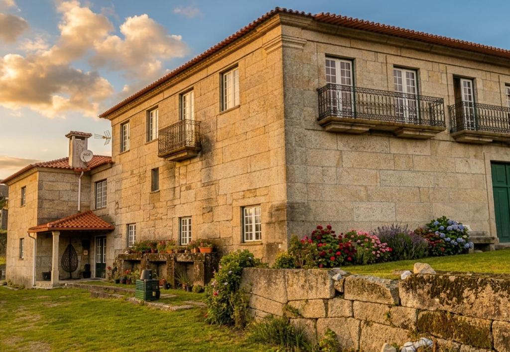 a large stone building with balconies and a yard at Casa do Cabo in Ribeira de Pena