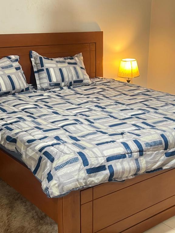 a bed with a blue and white comforter and a lamp at Rufisque Dakar en face de la plage in Mbaw