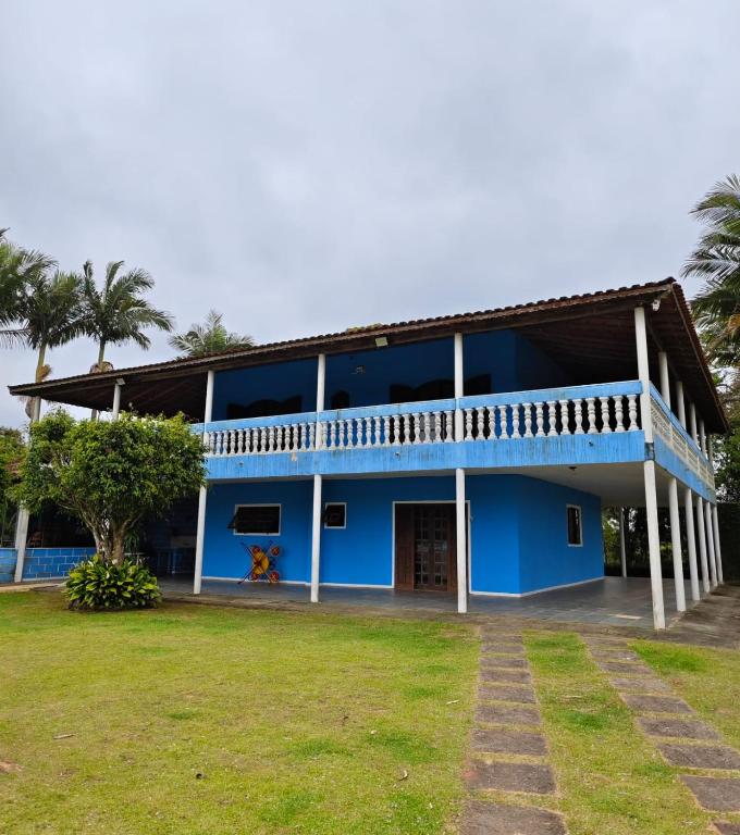 a blue building with a balcony and a yard at Chácara Segatelli in Cotia