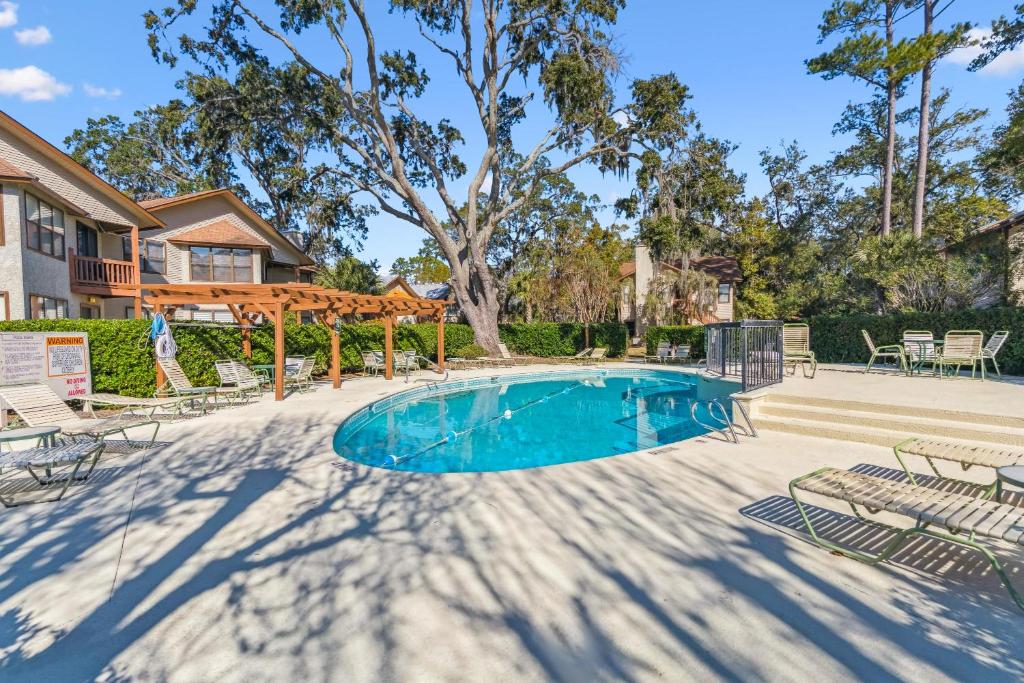 a swimming pool with chairs and a tree at Harbour Oaks, Unit 419 in Saint Simons Island