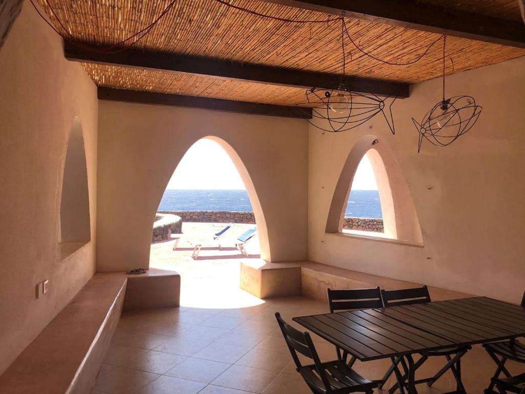 a dining room with a table and two arched windows at Mare Infinito in Pantelleria