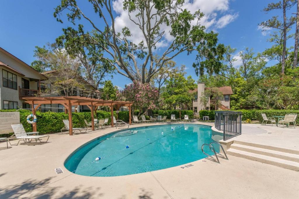 a swimming pool with chairs and a gazebo at Harbour Oaks, Unit 413 in Saint Simons Island