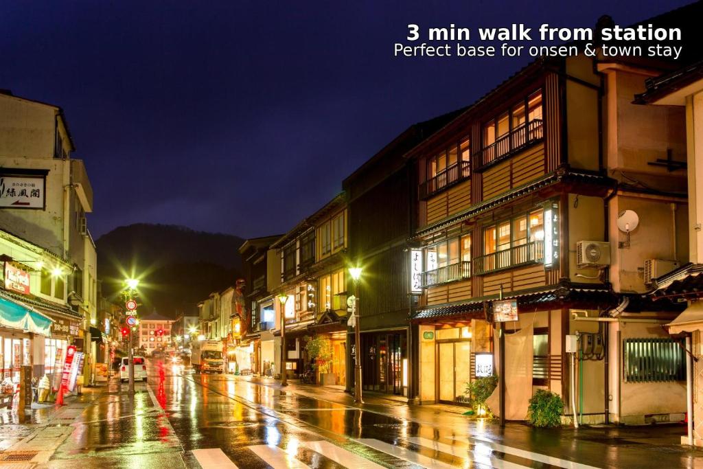 a wet city street at night with buildings at Yoshiharu in Toyooka