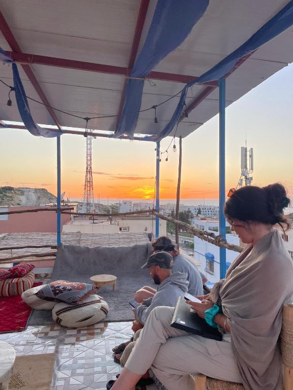 a group of people sitting on a bench watching the sunset at Tayri Surf House Aourir in Agadir