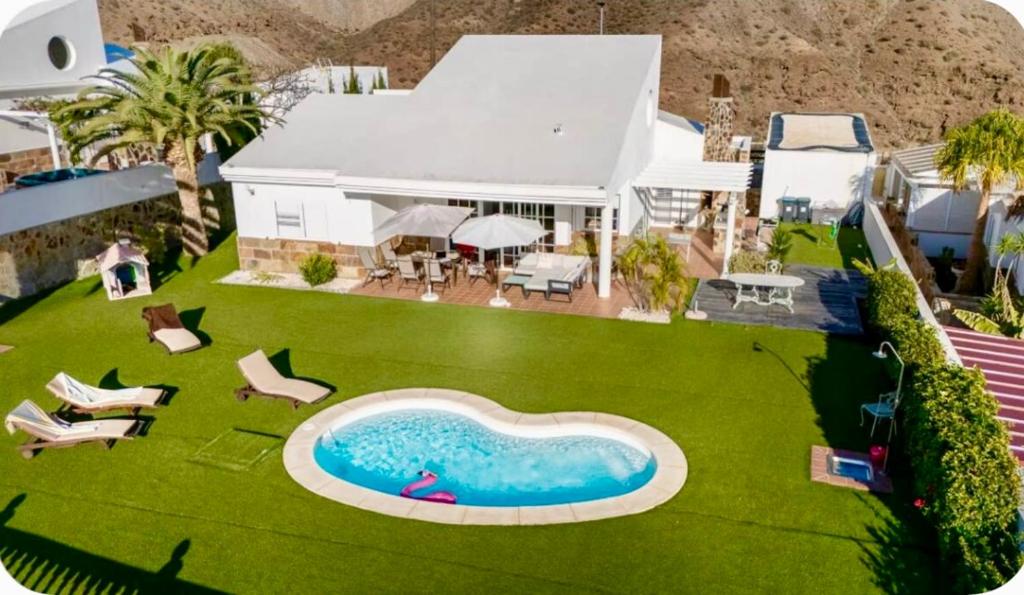 a house with a swimming pool on a green lawn at Casa Alegria in Puerto Rico de Gran Canaria