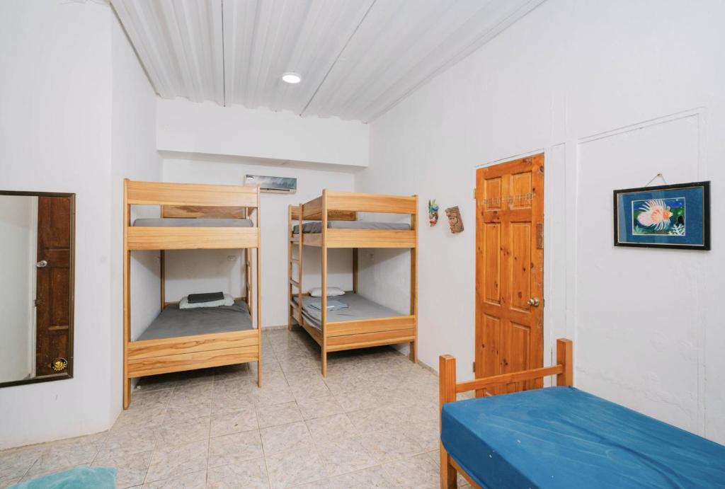 a room with a bed and a bunk bed and a door at Avellanas Surf Hostel in Playa Avellana