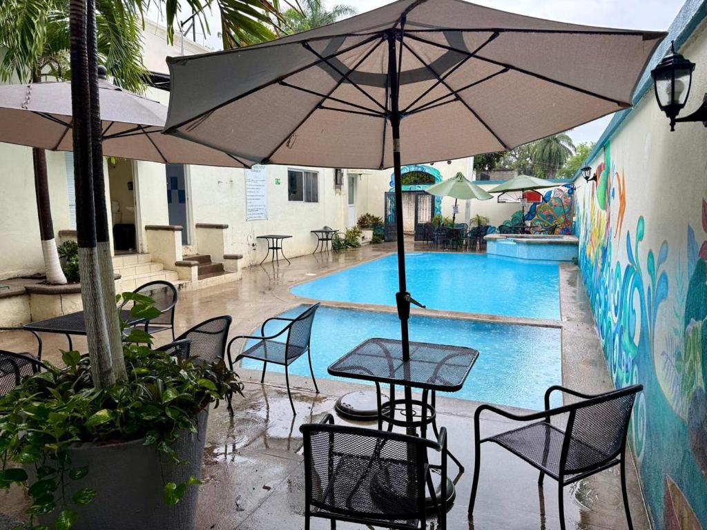 a table and chairs with an umbrella in front of a pool at Mega Suite en Hotel Cosmos in Tamasopo