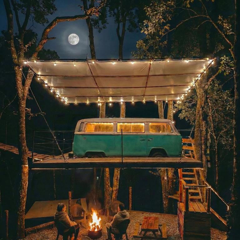 a van under a canopy with people sitting around a fire at Biciting Combi Love Glamping with Jacuzzi and Views in Mineral del Chico