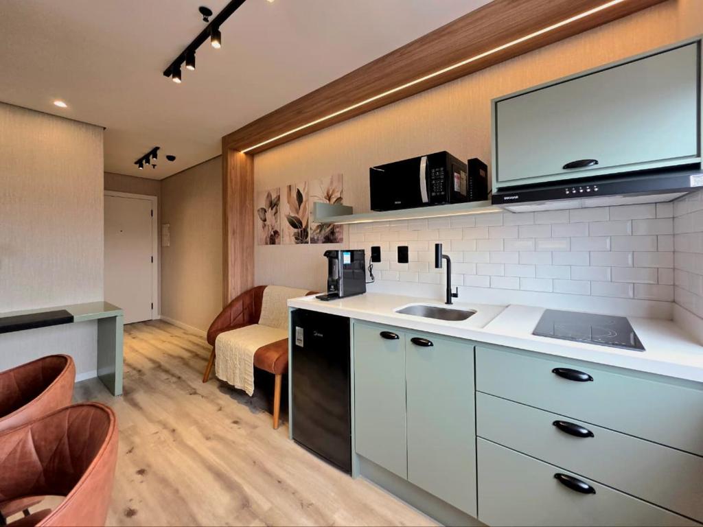 a kitchen with a sink and a living room at Flat Premium Design Moderno, Completo in Osasco