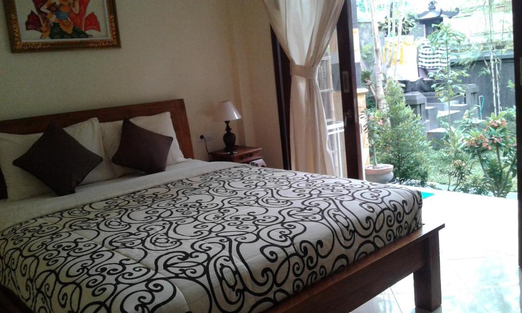 ein Schlafzimmer mit einem Bett und einem großen Fenster in der Unterkunft Uma Taman House in Ubud