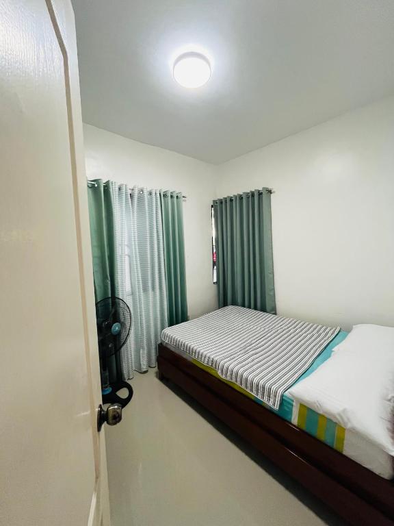 a small bedroom with a bed and a window at Akina 2bedroom Transient House in Kabankalan