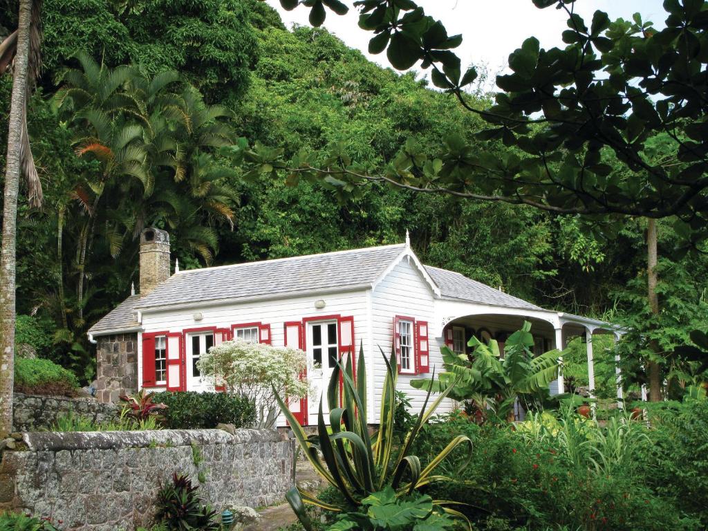 a red and white house in a garden at House On The Path in Windward Side