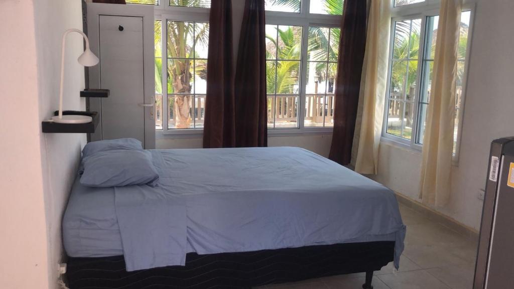 a bedroom with a bed in a room with windows at La casa de Fercho in Sipacate