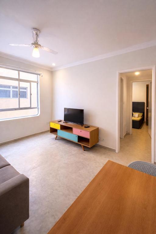 a living room with a couch and a tv at Apê Completo - 300m da Praia in Guarujá