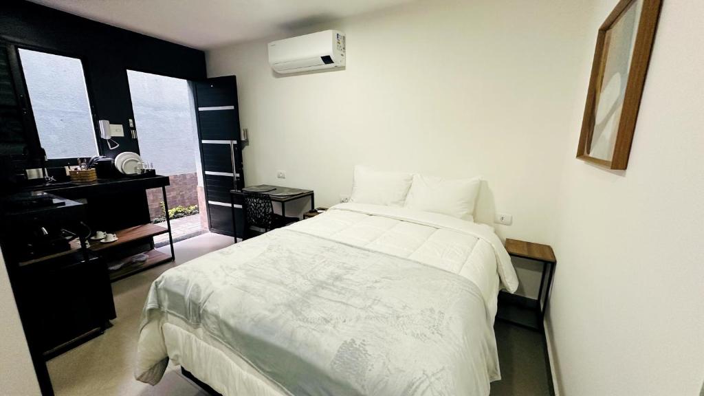 a bedroom with a bed with white sheets and a window at Chacara Stay in São Paulo