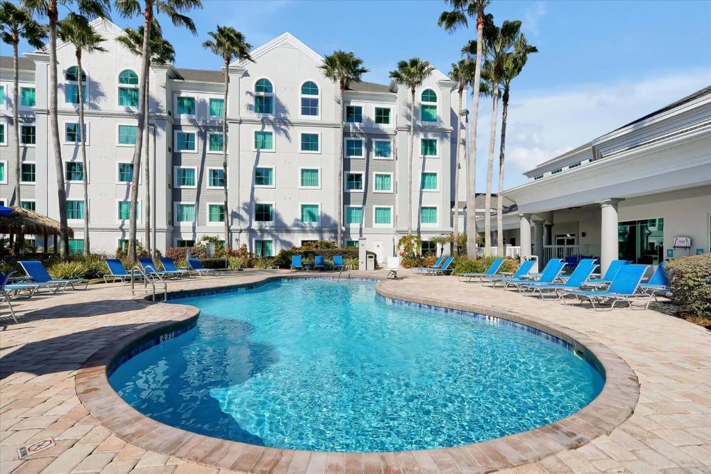 a pool in front of a hotel with chairs and a building at Pool View DisneyUniversalFree ShuttleParking in Orlando