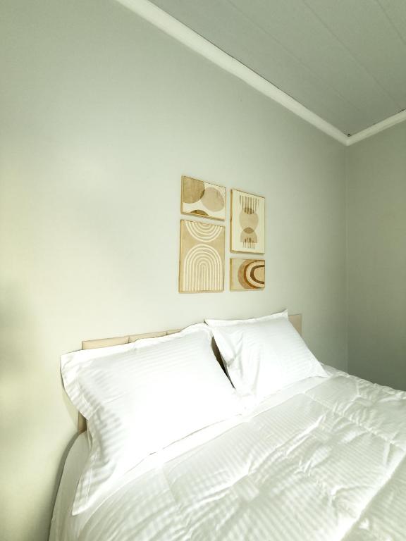 a white bed in a bedroom with two pictures on the wall at Apartamento Super Conforto in Naviraí