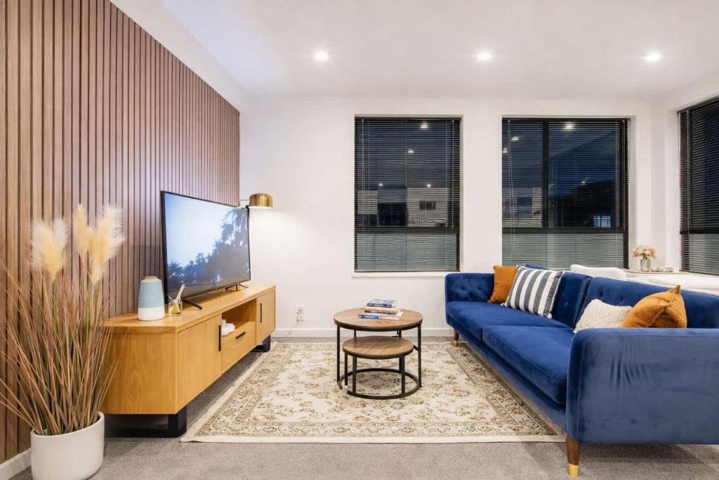 a living room with a blue couch and a tv at Fitzgerald Focus - Your 1BR Urban Oasis in Christchurch