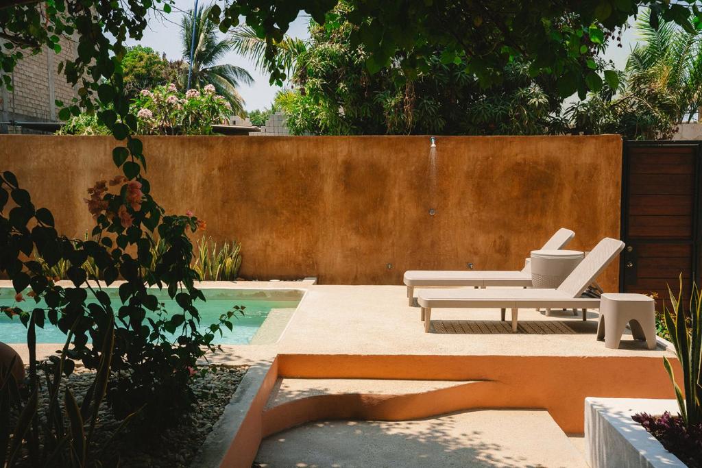 a patio with two white chairs and a pool at Maralagua in Puerto Escondido