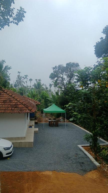 a patio with a green umbrella next to a building at Kanthanpara mist stay in Meppādi