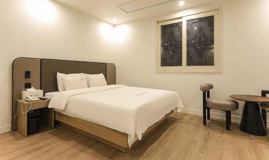 a bedroom with a large white bed and a table at Vov Hotel in Busan