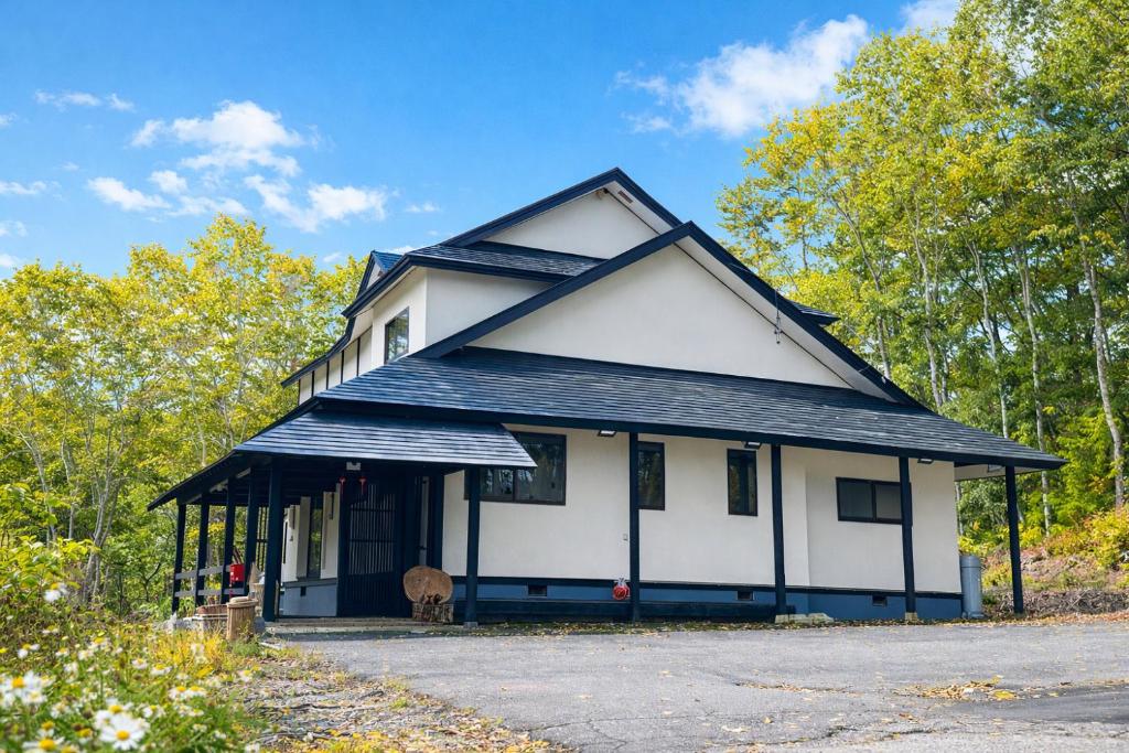 a white and black house with a dog in front at Fuji-Kurohime- in Shinano