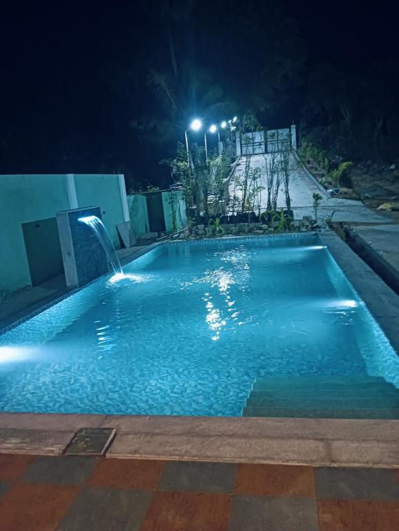 an empty swimming pool at night with lights at hariholidaysvilla in Chennai