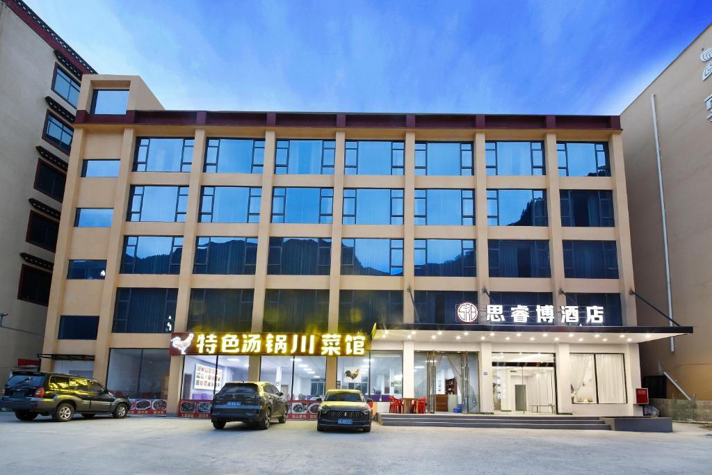 a building with cars parked in front of it at 四川思睿博酒店 in Heishui