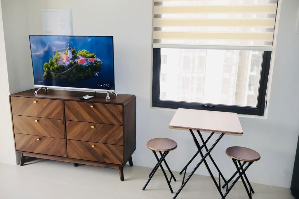 a tv sitting on top of a dresser next to two stools at Studio Getaway in Cebu City Baseline in Cebu City