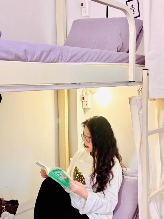 a woman reading a book in a bunk bed at Da Nang Sleepbox & Dorm in Danang