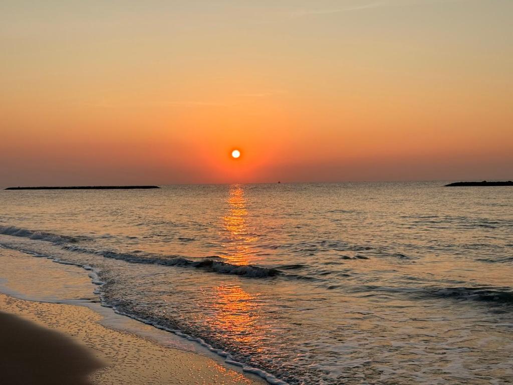 a sunset on the beach with the sun setting at Wind Haus Beachfront Villa in Ban Hat Chao Samran