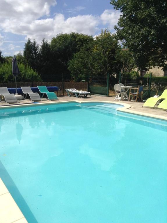 a large blue swimming pool with chairs and tables at La Roseraie in Romagne