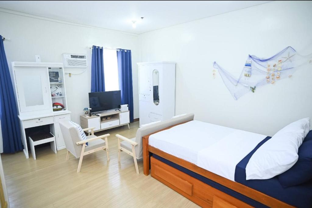 a bedroom with a bed and a desk with a television at Condotel in SM Trece Martires in Trece Martires