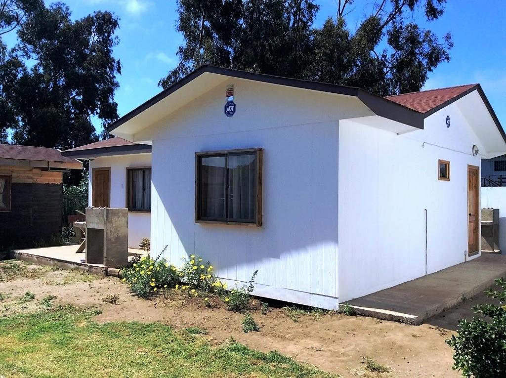 a white house with a window in a yard at Cabañas Vista Parapentes in Maitencillo