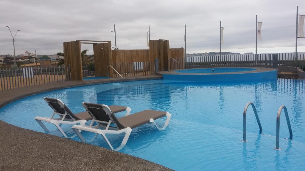 una piscina con 2 sillas en el agua en Departamento En Arena Maris, en Algarrobo